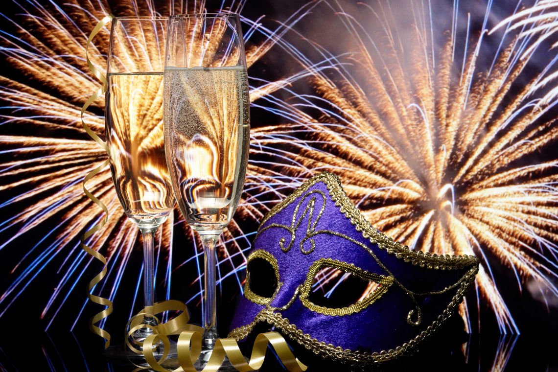 Glasses with champagne and Venetian mask against fireworks